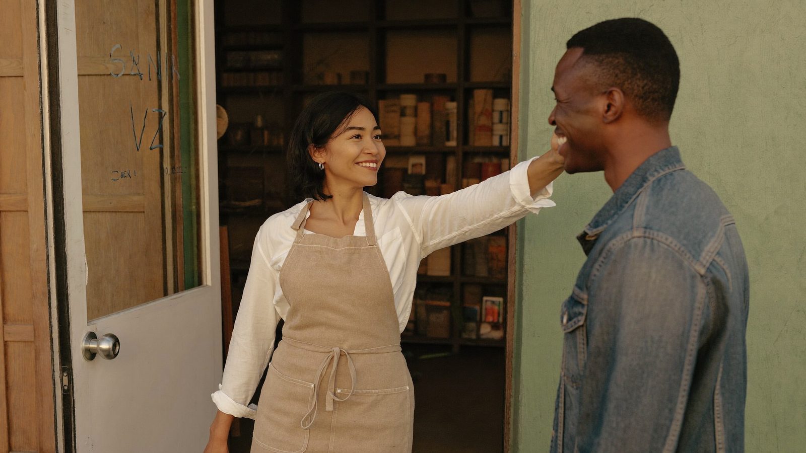 A small business owner shares a warm conversation with a returning customer at the front door of her shop