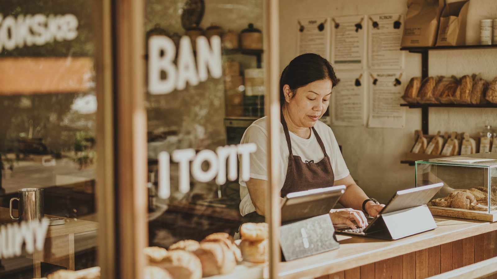 A small bakery owner reviewing her accounts calmly on a laptop at the counter before opening