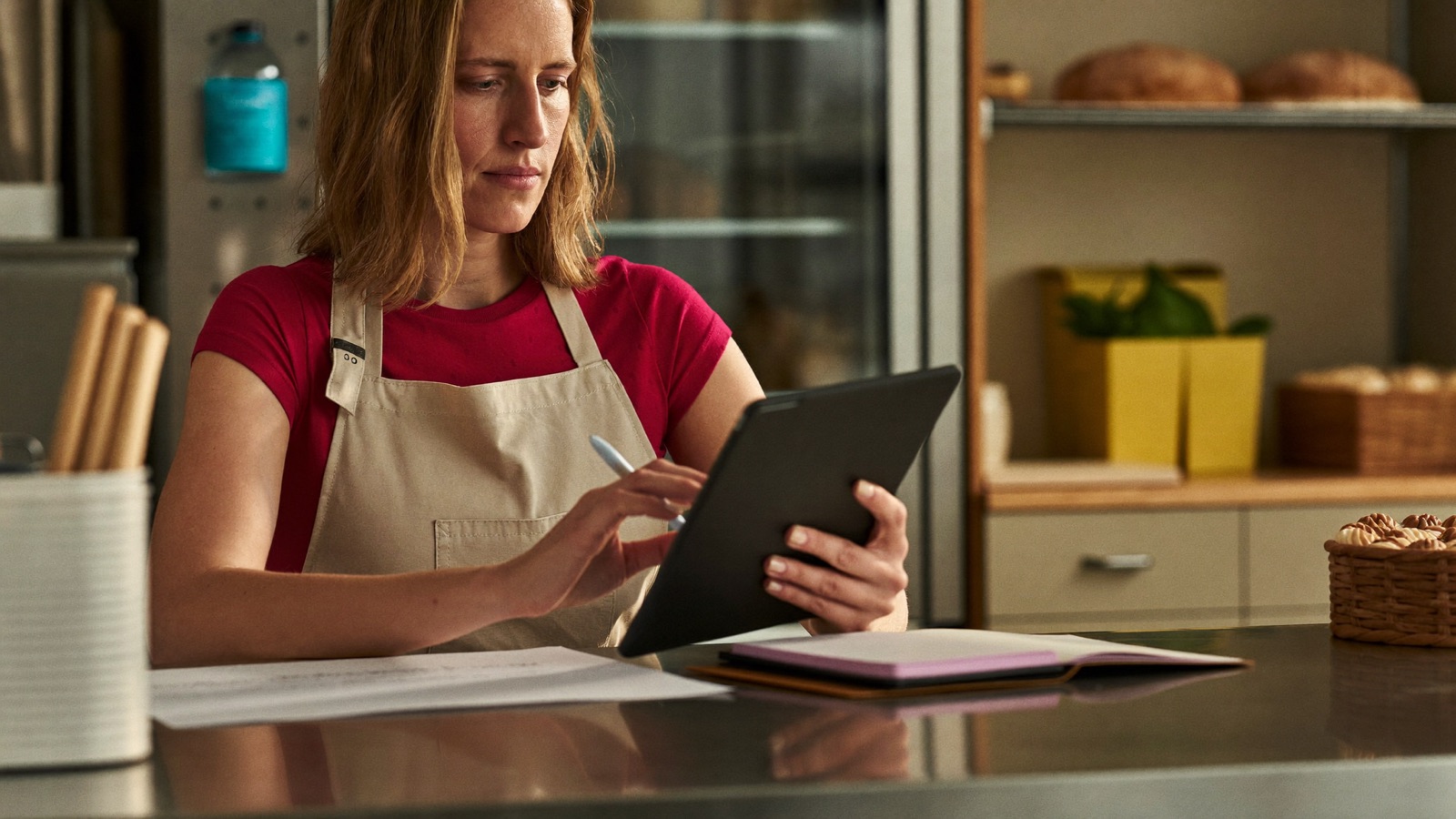 A bakery owner works through the numbers on a tablet at her counter