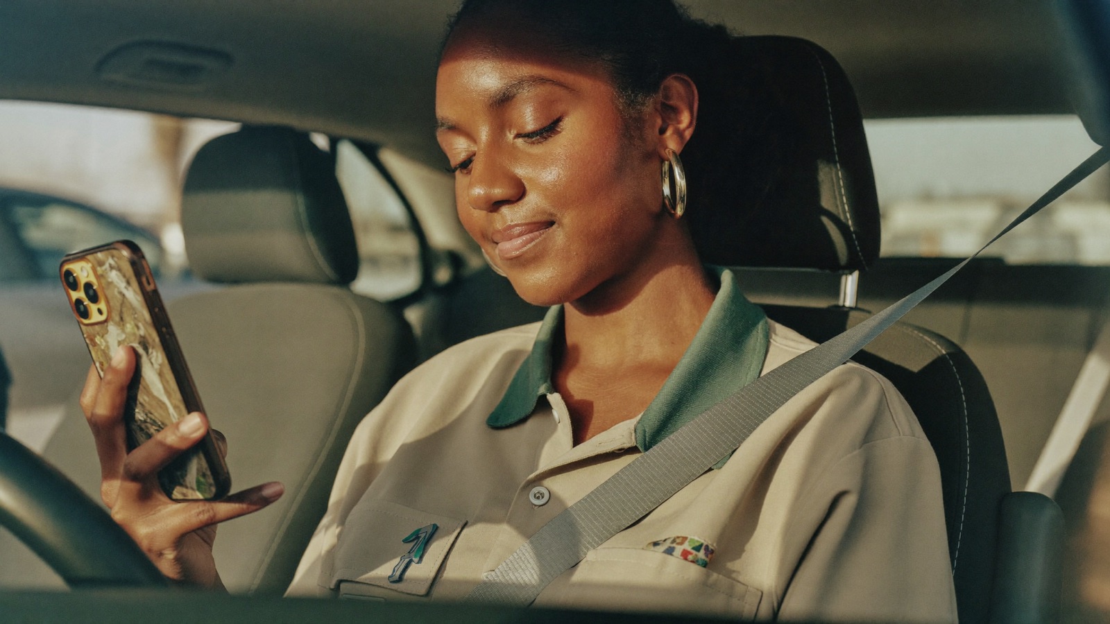 A field-service technician reads a text message on her phone in the cab of her work van